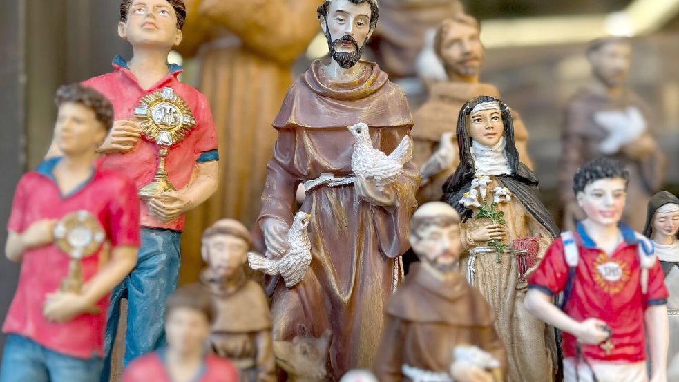 Figuren des alten und des neuen Heiligen stehen in Souvenirshops nebeneinander. (Archivbild) Foto: Christoph Sator/dpa