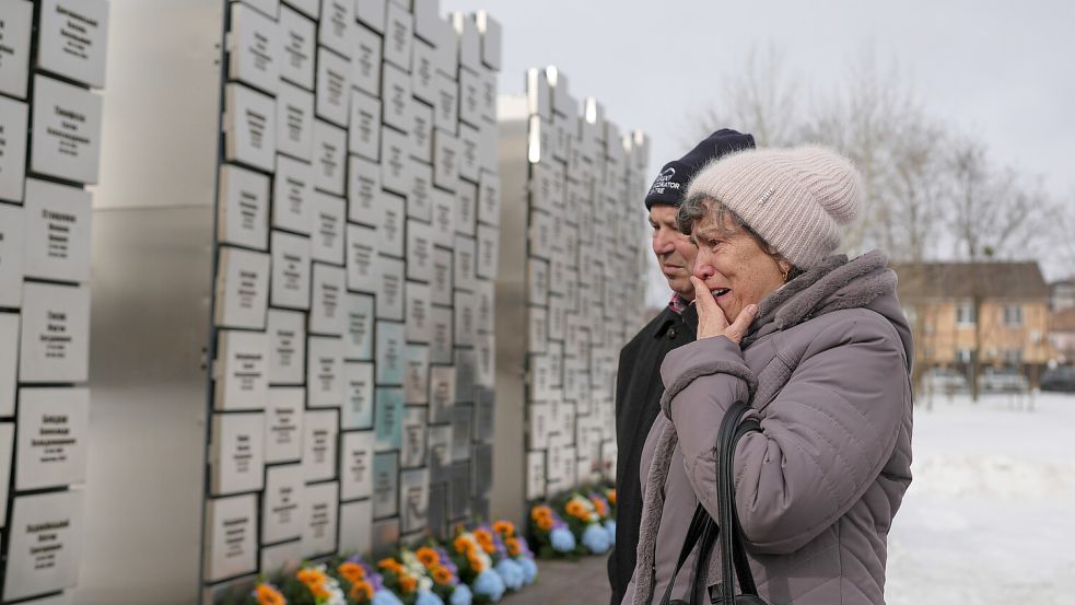 Angehörige von Menschen, die während der russischen Besatzung in der Ukraine getötet wurden, reagieren an der Mauer der Erinnerung in Bucha während einer Zeremonie zum vierten Jahrestag der russischen Invasion. Foto: DPA