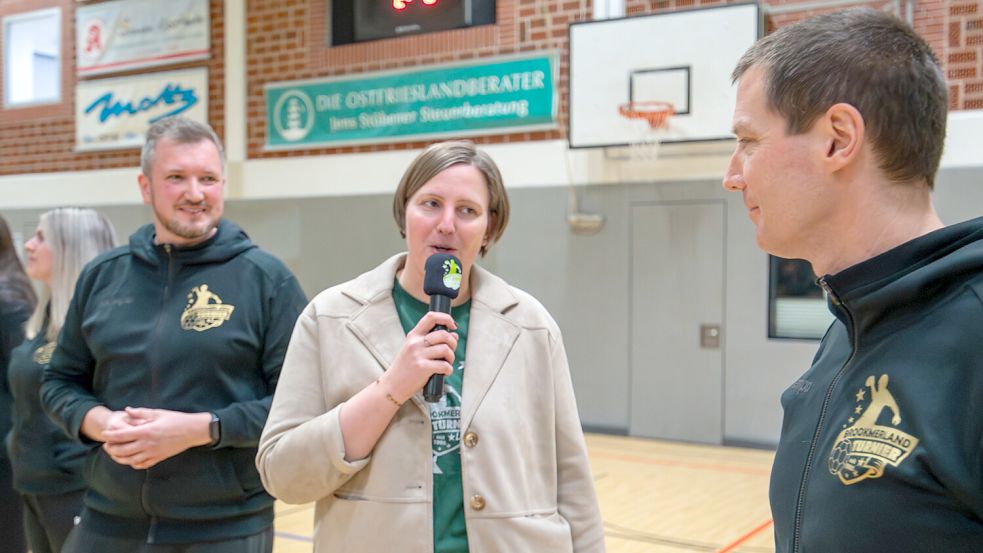 Andrea Janssen-Zimmermann gilt als volksnahe und weltliche Pastorin. 2025 übernahm sie die Schirmherrschaft des Handballturniers in Marienhafe. Das Bild zeigt sie im Gespräch mit Turniersprecher Imko Swieter (links) und Cheforganisator Peter Adena (rechts). Foto: Folkert Bents