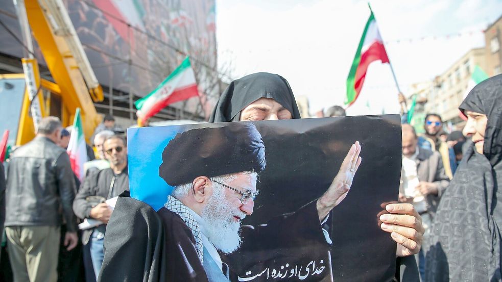 Eine Trauernde hält beim Begräbnis des von Israel getöteten Generalsekretärs des iranischen Sicherheitsrats, Ali Laridschani, ein Bild des ebenfalls getöteten Obersten Führers Ajatollah Ali Chamenei in die Höhe. Foto: Stringer/dpa