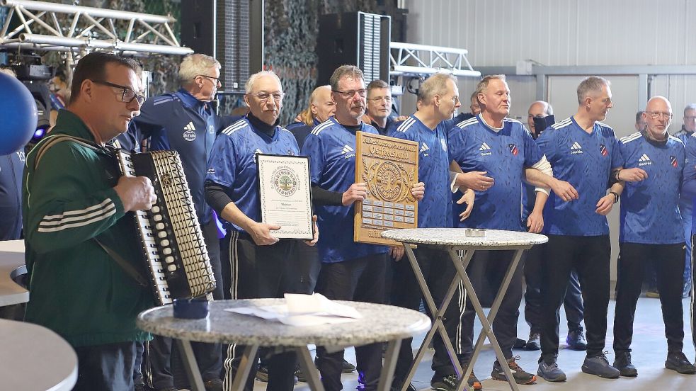 Der Ludwigsdorfer Gerd Hölscher (links) spielte Akkordeon, während die Pfalzdorfer Meisterboßler schunkelten. Eckhard Kerl (Dritter von links) und Alwin Jurisch hielten die Urkunde und die Trophäe des Titelträgers. Fotos: Wilfried Gronewold