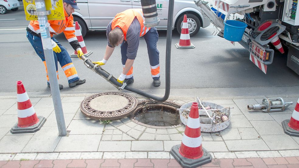 Arbeiter reinigen mithilfe eines Spülwagens die Kanalisation. Foto: Maja Hitij/DPA