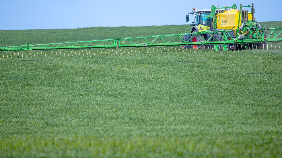 Ein Traktor zieht eine Spritze mit breiten Auslegern und verteilt Dünger auf einem Feld. Die Preise für Düngemittel sind aktuell hoch. Foto: DPA