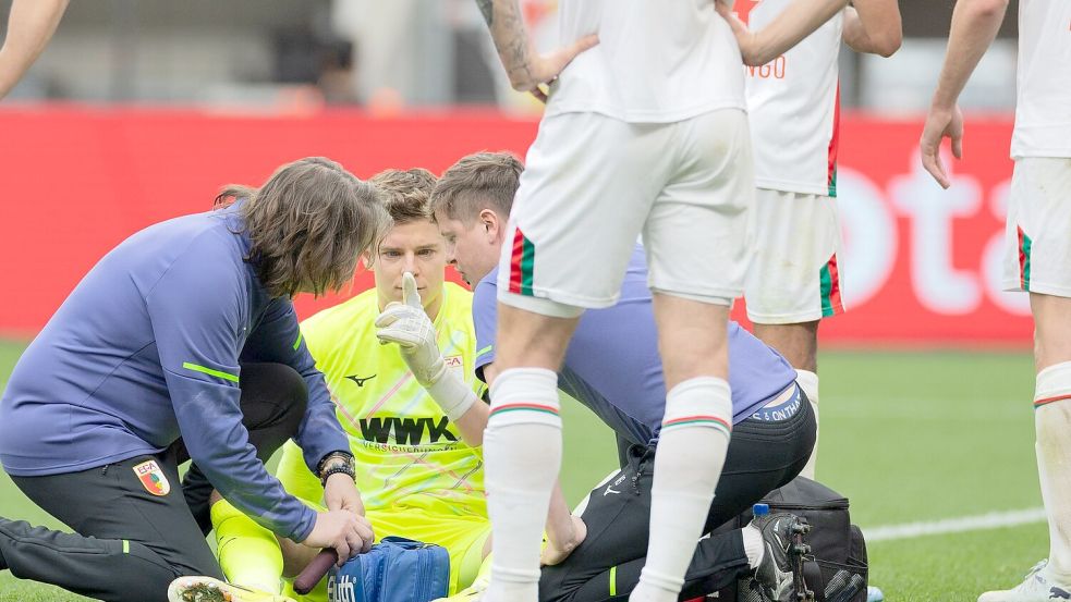 Auch eine kurze Behandlungspause nach einer Abwehr mit dem Kopf konnte Augsburgs Keeper Finn Dahmen nicht aus dem Rhythmus bringen. Foto: Rolf Vennenbernd