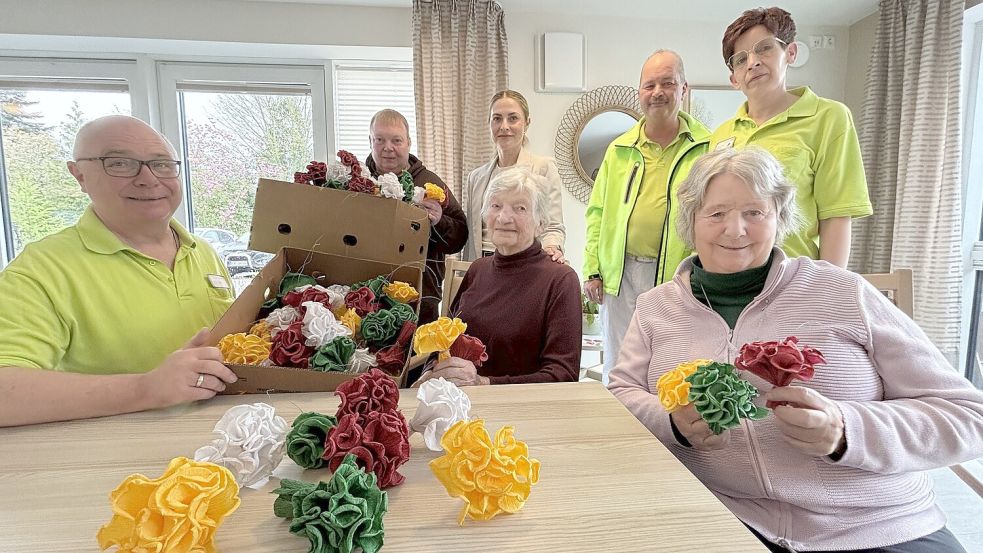 Edda Müller-Seedorf (vorne, von rechts) und Anneliese Egert gehörten am Montag zu den 15 Bewohnerinnen des Rosentors, die Maibaumrosen banden. Unterstützt wurden sie von Silke Hinrichs (hinten, von rechts), Harald Aukes, der stellvertretenden Einrichtungsleiterin Olga Müller, dem stellvertretenden Ortsbürgermeister Rolf Stemmler und Matthias Triebler. Foto: Karin Böhmer