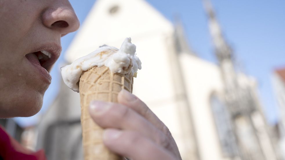 Eine Frau isst eine Kugel Eis in der Waffel. Foto: Marijan Murat/DPA