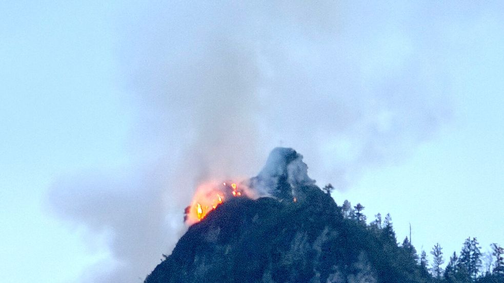 Noch immer steigen große Rauchwolken aus einem bewaldeten Berg bei Ruhpolding (Landkreis Traunstein) auf. Foto: Matthias Brüning/dpa