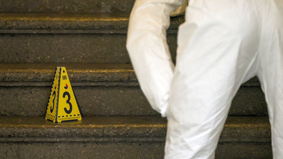 Ein Beamter der Spurensicherung der Polizei arbeitet im Treppenhaus eines Mehrfamilienhauses. Foto: dpa/Christoph Reichwein