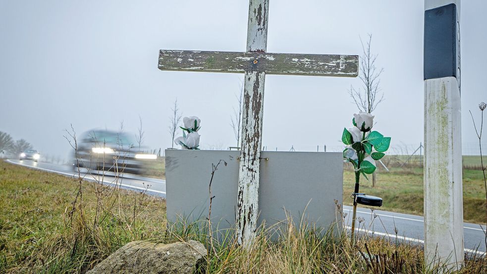 Ein Auto fährt auf einer Landstraße an einem hölzernen Kreuz vorbei, welches zur Erinnerung an ein Unfallopfer aufgestellt wurde. Foto: dpa/Jens Büttner