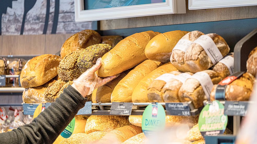 Eine Verkäuferin greift nach einem Brot in der Auslage einer Bäckerei. Foto: Mohssen Assanimoghaddam/DPA