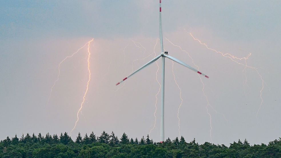 Blitze eines Gewitters leuchten über der Landschaft mit einer Windenergieanlage. Foto: Patrick Pleul/dpa