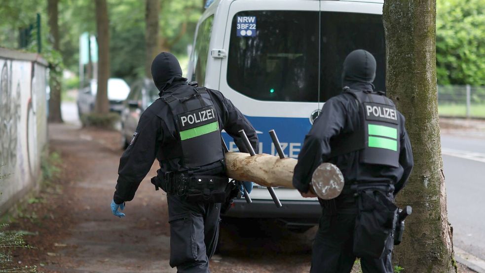 Polizisten tragen einen Rammbock. Foto: Christoph Reichwein/dpa