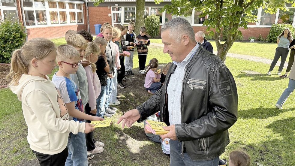 Fachausschussvorsitzender Berthold Lübben (rechts) verteilte gemeinsam mit Bürgermeister Thomas Erdwiens und Gerd Rinderhagen von der Kultur-AG die Ferienpässe an der Grundschule in Victorbur. Foto: Holger Janssen