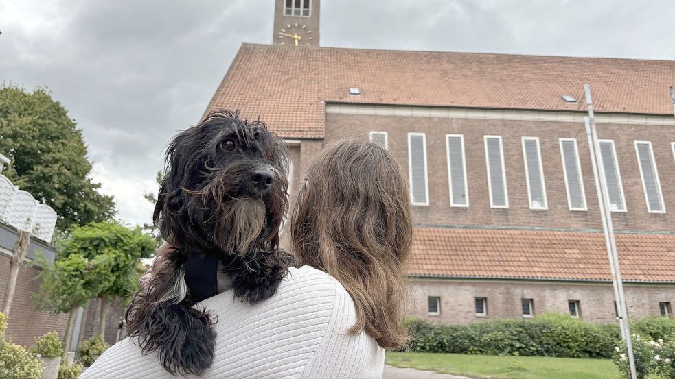 Hundemädchen Frieda dürfte jetzt in Emden mit zu einem Gottesdienst der Martin-Luther-Gemeinde. Die Kirche an der Bollwerkstraße ist im Hintergrund zu sehen. Der Gottesdienst am 14. Juni wird aber auf einer Wiese am Gemeindehaus Conrebbi abgehalten. Foto: Mona Hanssen/Archiv