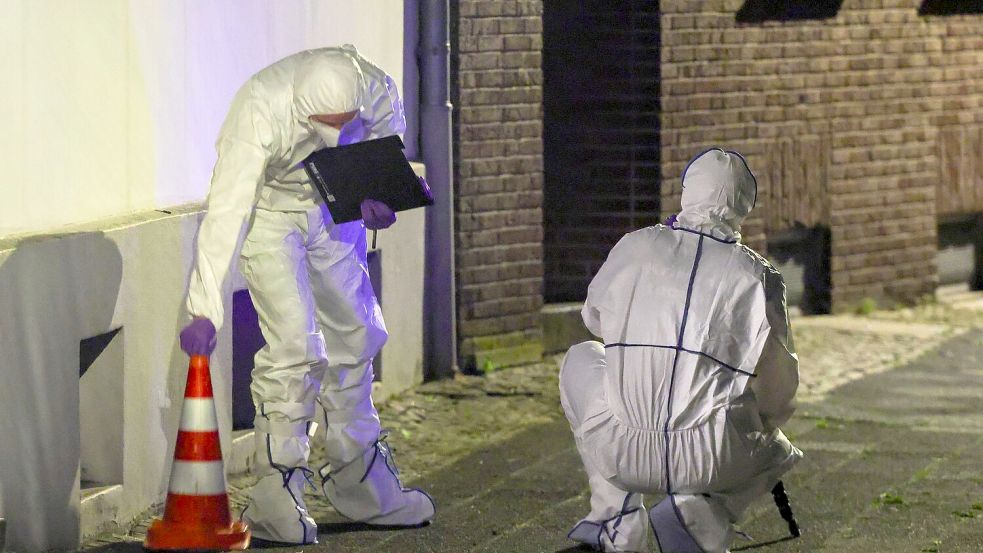 Beamte der Spurensicherung in Spurensicherungsanzügen begutachten den Tatort. Foto: Christoph Reichwein