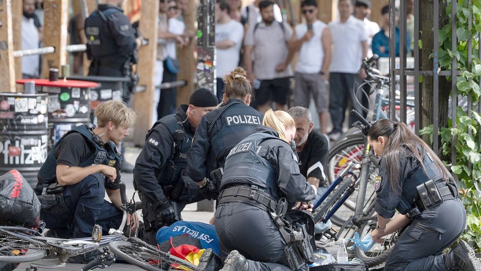 Polizisten knien in der Nähe des Frankfurter Hauptbahnhofs am Boden und kümmern sich um einen Verletzten. Foto: Boris Roessler