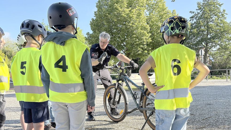 Polizeioberkommissar Ewald Einnolf nimmt vor der Prüfung die Räder der Kinder unter die Lupe und bespricht mit ihnen, was alles zu einem verkehrssicheren Rad dazugehört. Unter anderem müssen sowohl die Vorderrad- als auch die Hinterradbremse funktionieren. Foto: Mieke Matthes