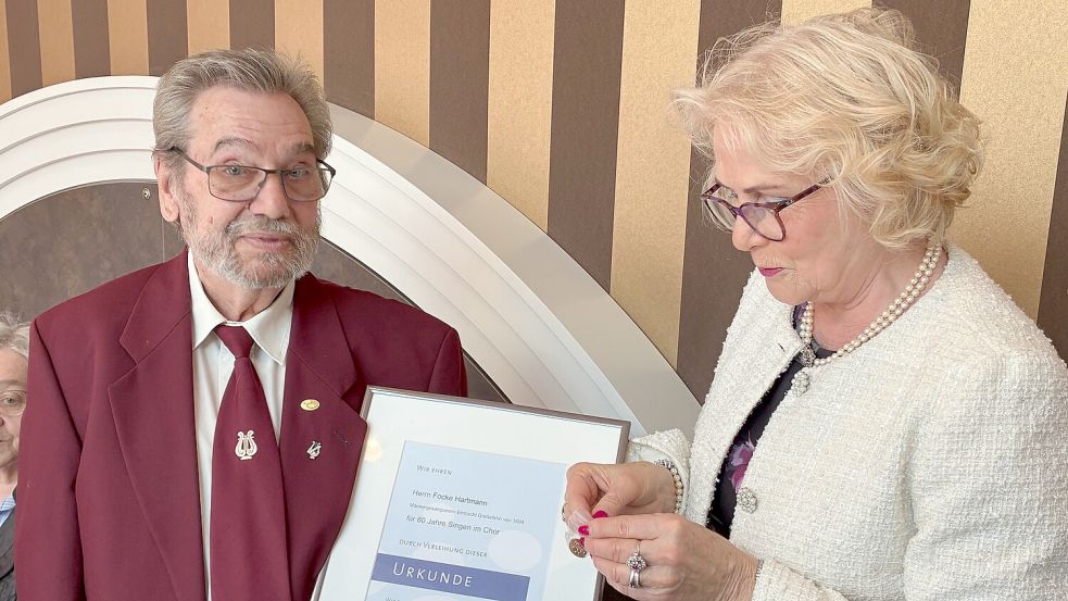 Für über 60-jährige Mitgliedschaft im Männergesangverein „Eintracht“ Großefehn wurde Vorsitzender Focke Hartmann mit Urkunde und Anstecknadel geehrt. Die Ehrung nahm Heike Douglas vor, Präsidentin des Ostfriesischen Chorverbandes. Foto: Detlev Schoone
