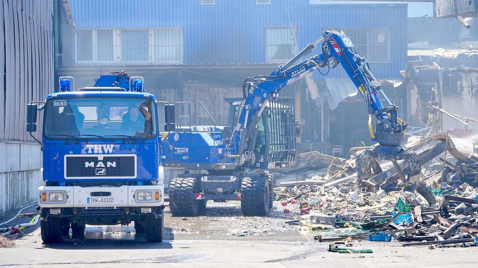 Einsatzkräfte des Technischen Hilfswerks (THW) beseitigen mit einem Bagger Schutt nach dem Feuer in einem Gewerbegebiet in Stuttgart. Foto: Enrique Kaczor/dpa