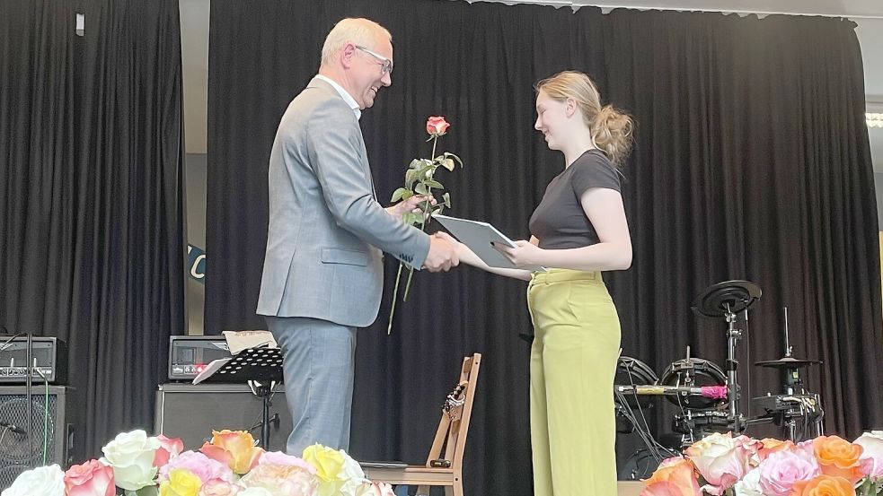 Schulleiter Christian Hunsmann überreicht einer Schülerin ihr Abschlusszeugnis. Foto: FCSO