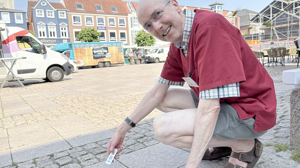 Apotheker Wolfgang Waßmus zeigt mit einem Infrarotthermometer, wie heiß das Pflaster auf dem Auricher Marktplatz werden kann. Foto: Archiv/Mieke Matthes