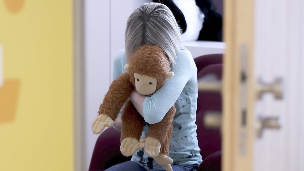 Eine junge Frau sitzt mit einem Kuscheltier im Arm in einem Raum des Childhood House, in dem Kinder und Jugendliche, die von Missbrauchs betroffen sind, vernommen werden können (gestellte Szene). Foto: dpa/Jan Woitas
