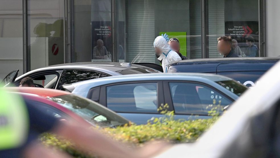Polizisten führten am Abend einen Mann in einem weißen Anzug aus dem Gebäude, wenig später wurde eine Festnahme vermeldet. Foto: Armin Weigel