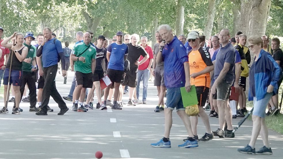 Auf der Spekendorfer Straße kommentiert der Pfalzdorfer Vereinsvorsitzende Frido Walter (blaue Jacke) mit dem Mikrofon in der Hand die Startwürfe der Boßlerinnen und Boßler. Foto: Helmut Vortanz