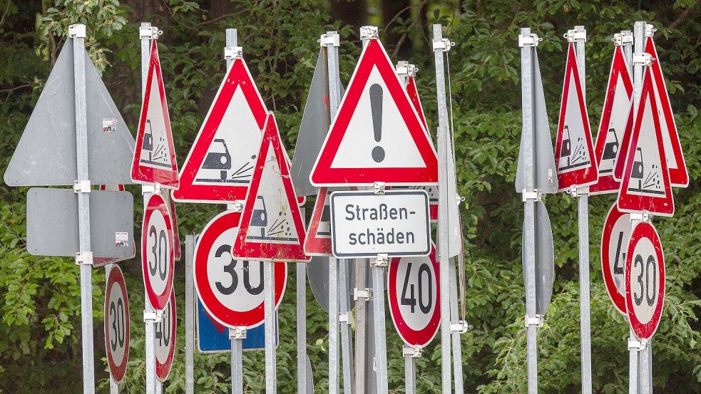 Verschiedene Verkehrsschilder, die auf Straßenschäden oder Geschwindigkeitseinschränkungen hinweisen, stehen auf dem Hof einer Kreisstraßenmeisterei. Foto: DPA