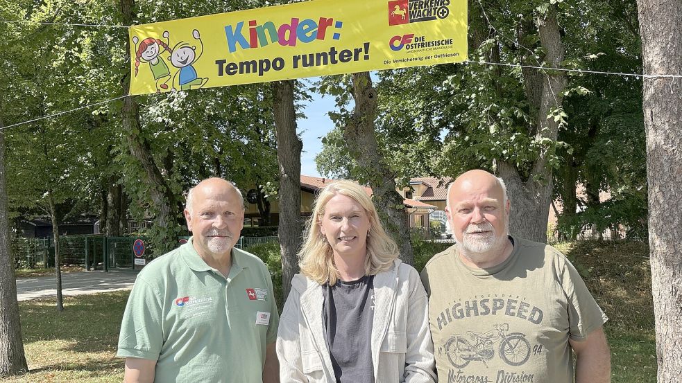 Friedel Walther (v.l., Verkehrswacht), Christin Wiese (Grundschule Wallinghausen) und Wilhelm Doden (Verkehrsforum Landkreis Aurich) mit einem der Banner, das Autofahrer auf den Schulstart hinweist. Foto: Mieke Matthes