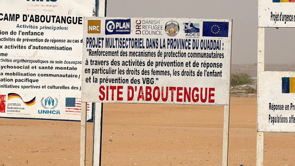 Auf dem Gelände eines Lagers für Flüchtlinge aus dem Sudan im Osten des Tschads stehen die Logos von Hilfsorganisationen, die dort im Einsatz sind. (Archivbild) Foto: Eva Krafczyk