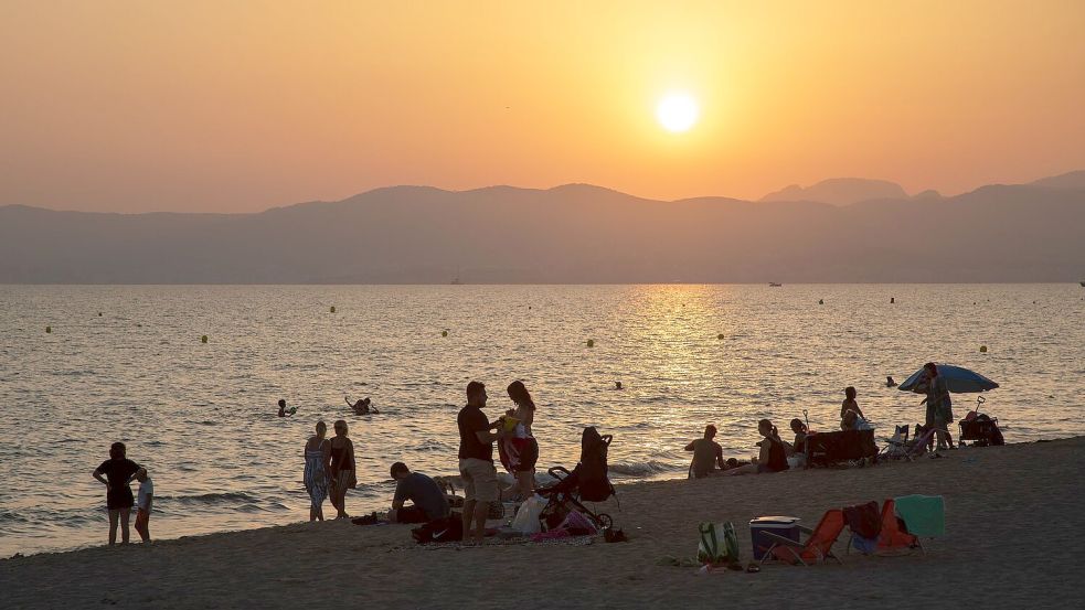 Am Strand von Playa de Palma auf Mallorca baden Menschen bei Sonnenuntergang im Meer. (Archivbild) Foto: Clara Margais