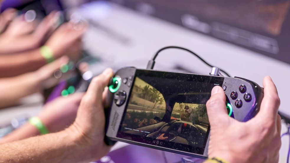 Ein Gamer hält bei der Gamescom 2025 ein Handheld-Device - eine Art tragbaren Mini-Gamingcomputer - in den Händen. (Archivbild) Foto: Oliver Berg