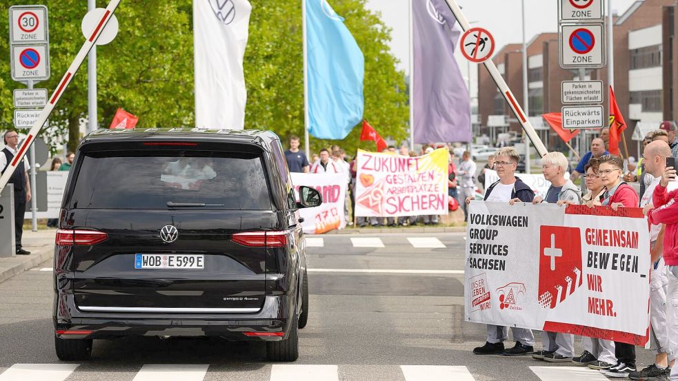 Ein VW-Bus mit VW-Vorstandschef Oliver Blume passiert die Demonstration von Beschäftigten am Werkstor des Standortes Zwickau. Foto: Hendrik Schmidt