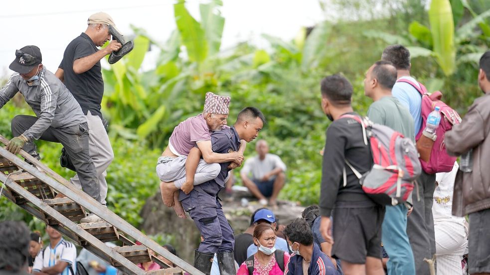 Ein Mann wird im Katastrophengebiet in Nepal von einem Polizisten auf dem Rücken getragen. Foto: Rajesh Kumar Singh