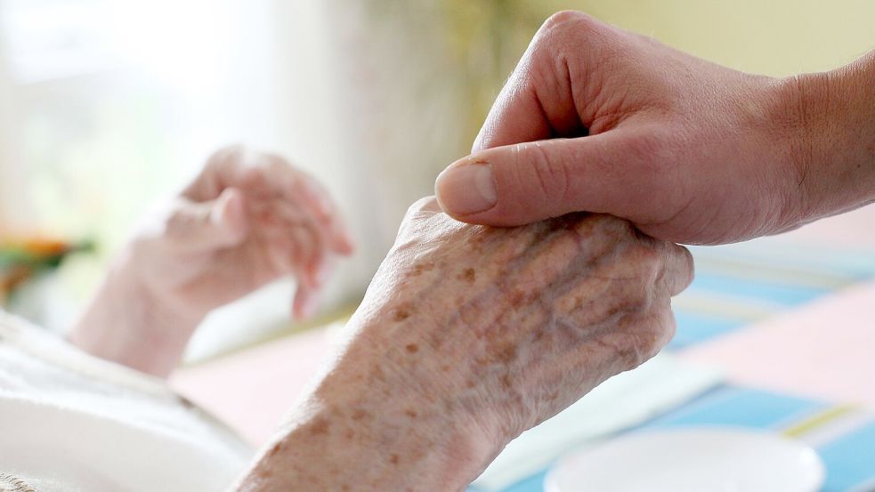 Ein Mitarbeiter eines Alten-und Pflegeheims hält die Hand einer Bewohnerin. (Archivbild) Foto: Oliver Berg/dpa