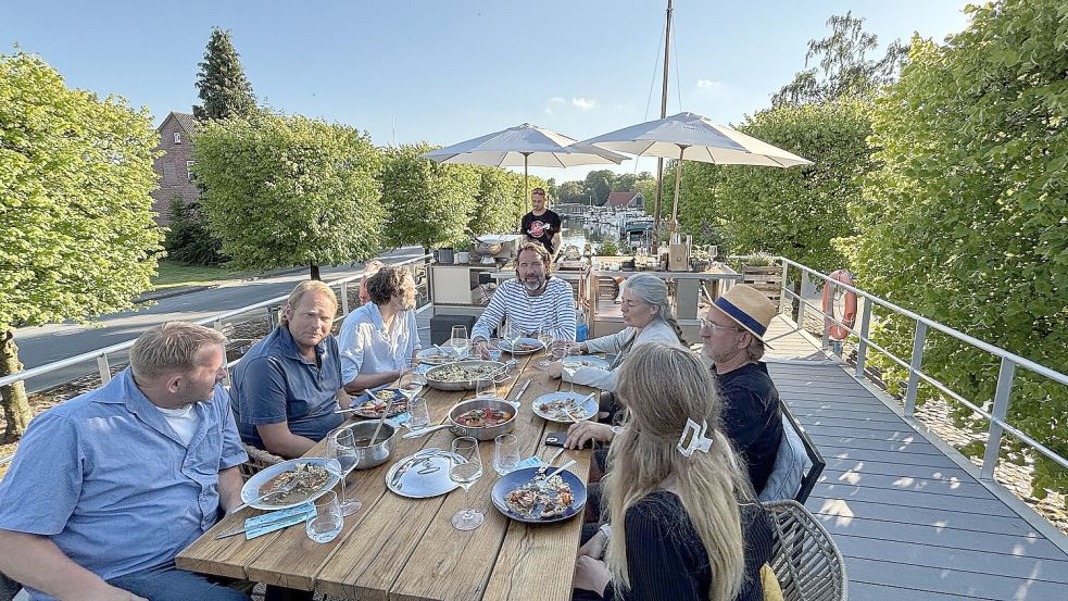 In der dritten Folge der ostfriesischen Lecker-an-Bord-Staffel sitzen Hermann Poppen (von links), Björn Freitag, Klaas Froschauer, Skipper Kai Linnenbrügger, Nadja Poppen, Frank Buchholz und Rieka Poppen gemeinsam am Tisch. Foto: Karin Böhmer