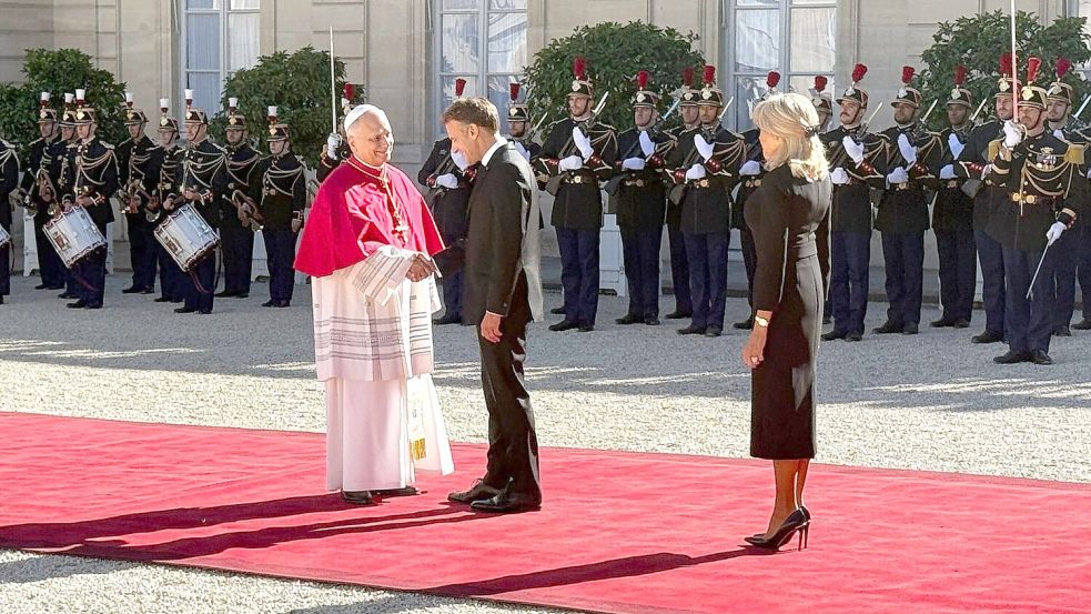 Frankreichs Präsident Emmanuel Macron und seine Ehefrau Brigitte schütteln Hände mit dem Papst im Hof des Élysée-Palastes. Foto: Christoph Sator/dpa