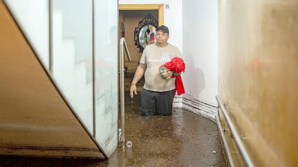 Ein Mann steht im Treppenhaus eines Gebäudes in der an Barcelona grenzenden Stadt L’Hospitalet de Llobregat in mehr als knietiefem Wasser.  Foto: Lorena Sopêna/EUROPA PRESS/dpa