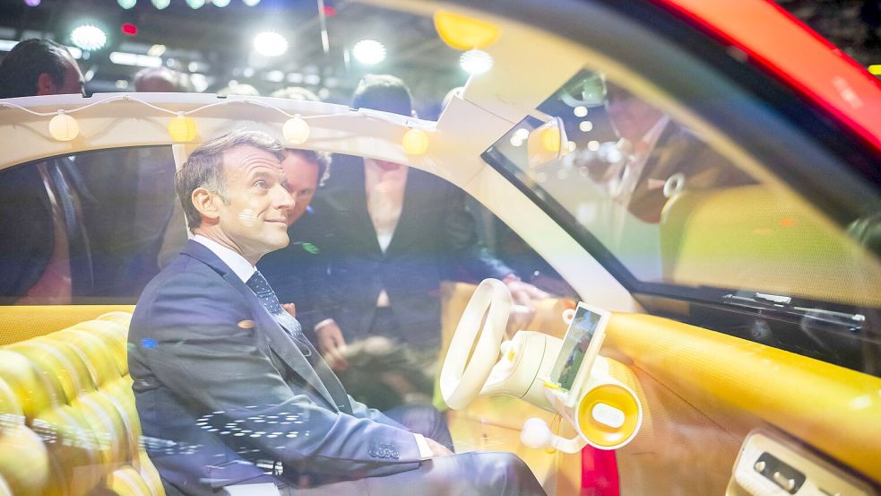Frankreichs Präsident Emmanuel Macron schaut belustigt in das Interieur der neuen E-Ente. Foto: IMAGO/Eliot Blondet / Pool / Bestimage