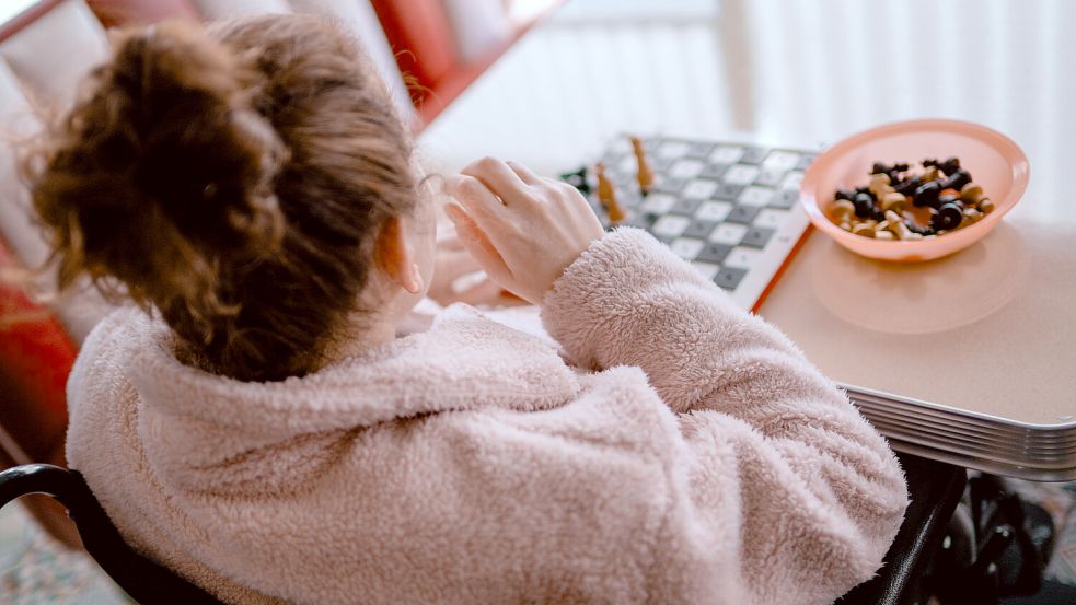 Miriam Krüger* spielt an ihrem Steckschachbrett. Die 29-Jährige ist wegen ihrer Kinderdemenz blind, findet in vertrauten Handgriffen aber noch Halt. Foto: Klaus Ortgies
