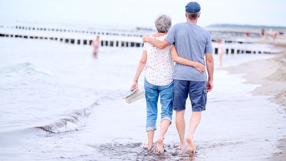 Ruhestand im Ausland? Ein Rentnerehepaar geht am Strand Arm in Arm spazieren. Foto: dpa/Annette Riedl