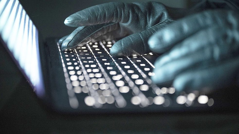 Eine Person tippt mit behandschuhten Händen auf einer beleuchteten Laptop-Tastatur. Foto: Philip Dulian/DPA