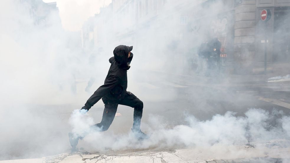 Ein Demonstrant wirft in Rennes eine Tränengasgranate in Richtung der Polizei. Foto: Jeremias Gonzalez/AP/dpa