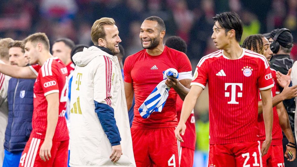 Die Bayern-Stars freuen sich für Harry Kane (weiße Jacke) und den noch fehlenden Trainer Vincent Kompany. Foto: Tom Weller/dpa